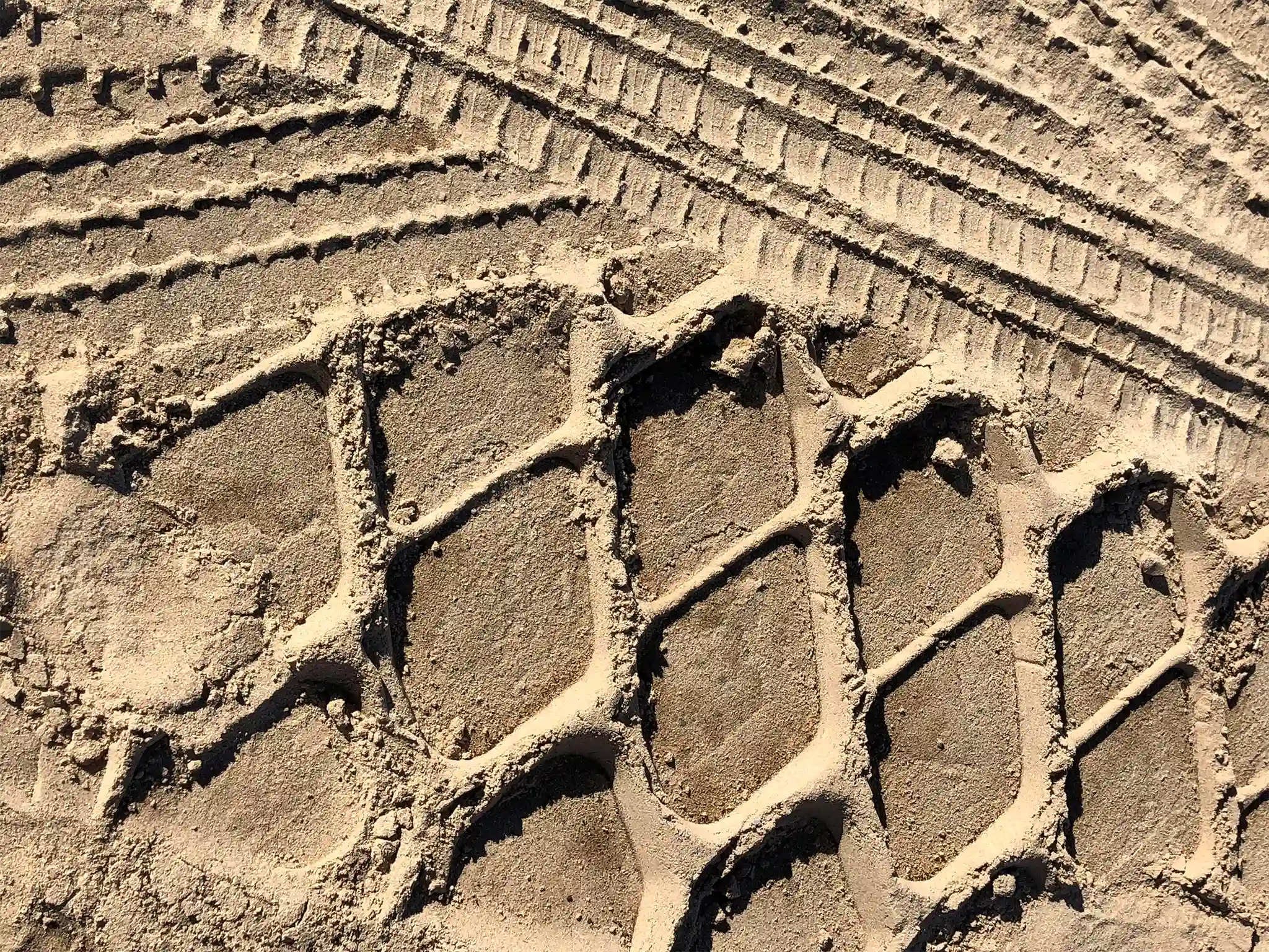 Tire tracks left in sand bytrucks and heavy equipment.