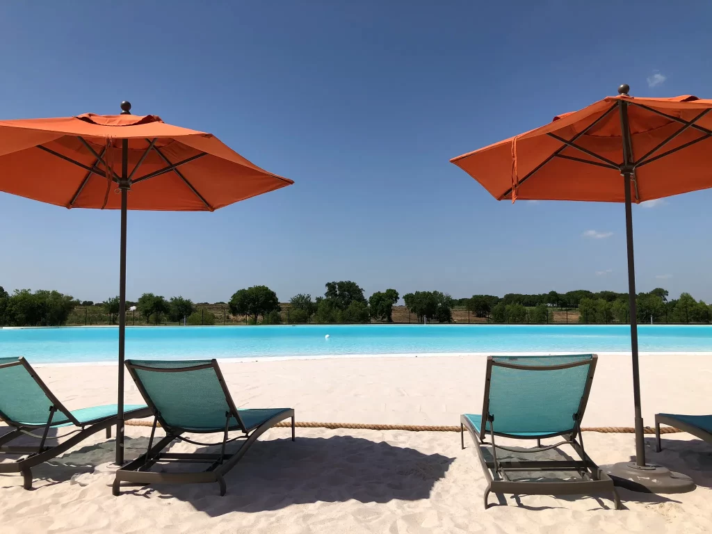 Fresh sand on a man-made beach with umbrellas and outdoor furniture.