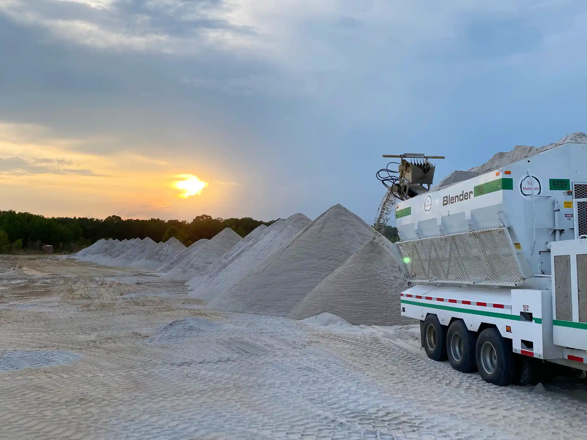 A truck filled with aggregate creates a pile of custom blended sand.