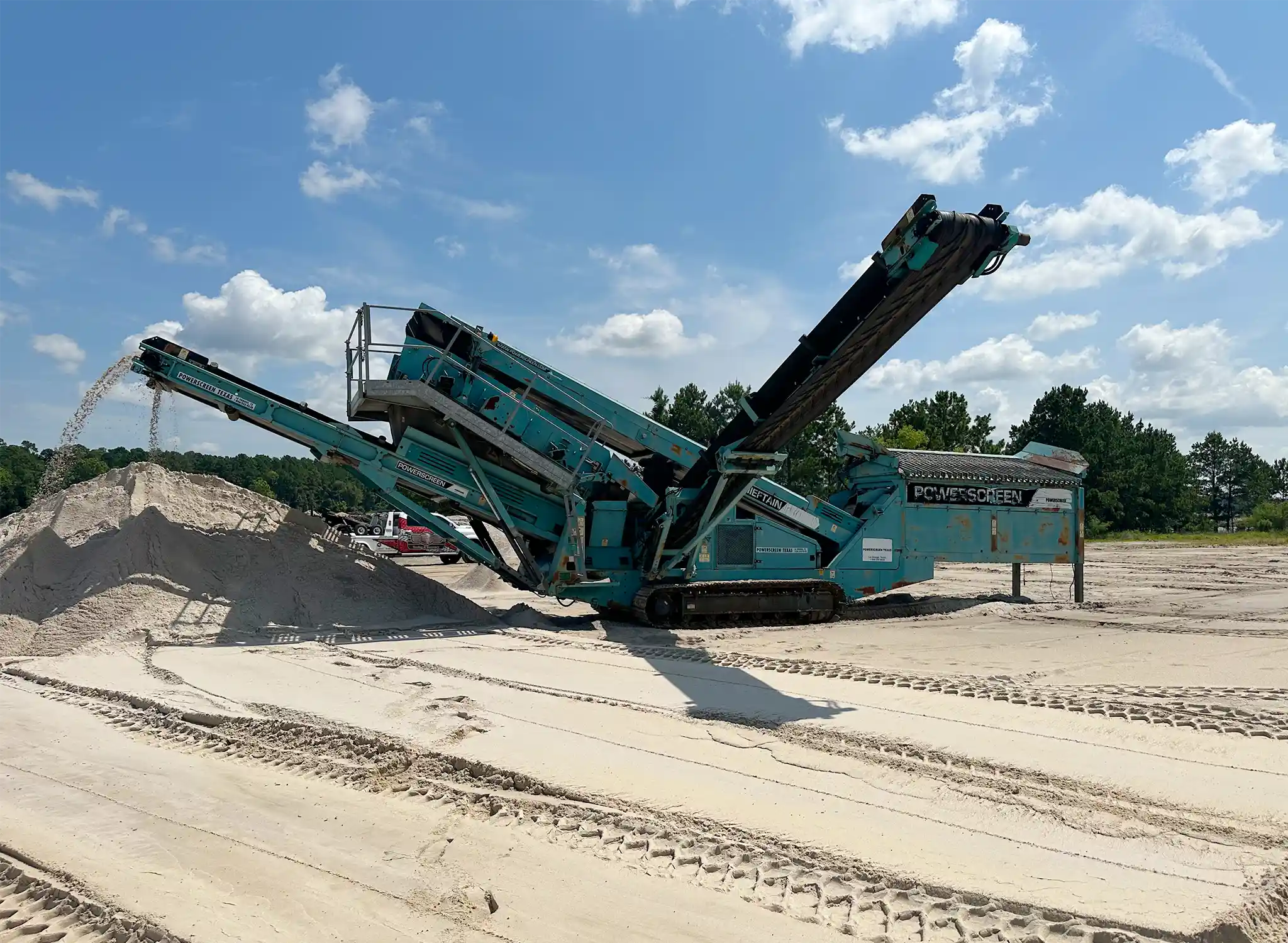 A power screener machine at work processing a batch of sand into piles.