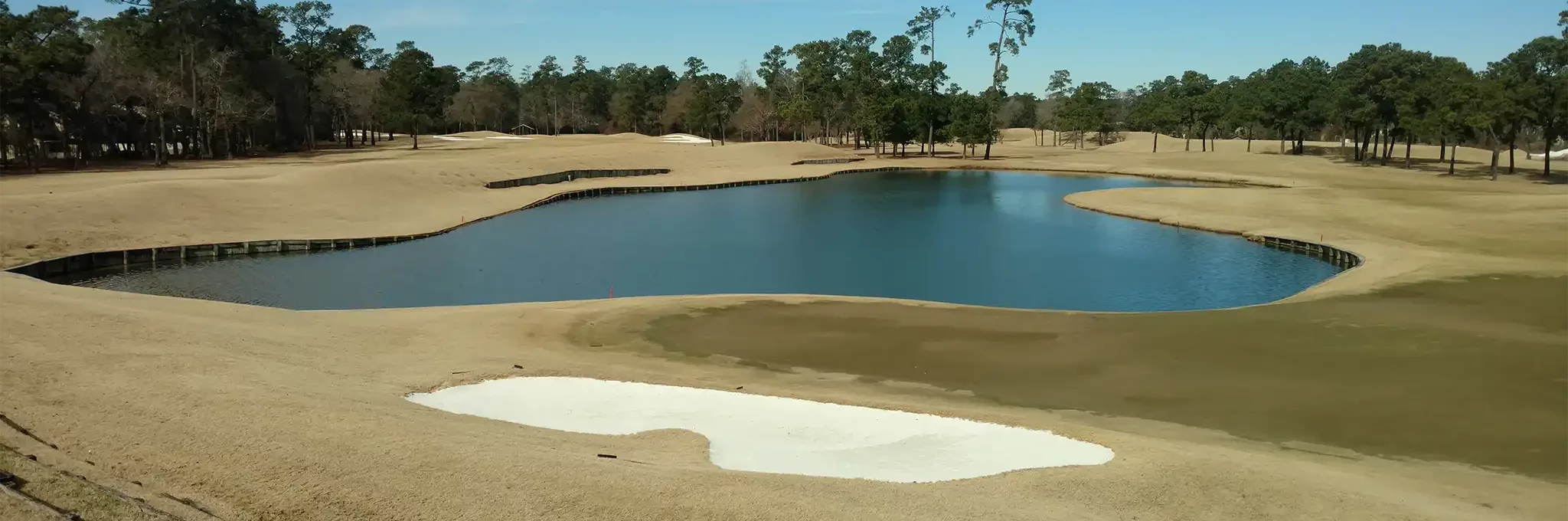 Premier White sand used in a golf course bunker with a lake and trees visible in the background.